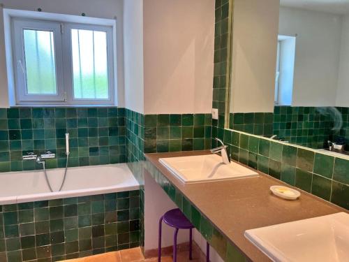 - une salle de bains carrelée de vert avec deux lavabos et une baignoire dans l'établissement Le Mas de L'Olivier, à Saint-Maurice-sur-Eygues