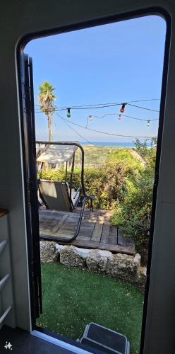 a view from a window of a porch with a swing at Countryside, beach view glamping caravan in HaBonim
