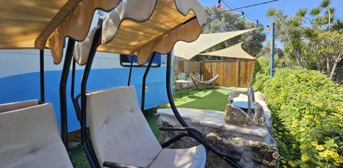 a patio with chairs and a hammock in a yard at Countryside, beach view glamping caravan in HaBonim