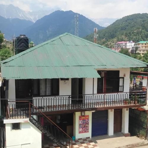 a building with a green roof with mountains in the background at Anchal House in Dharamshala