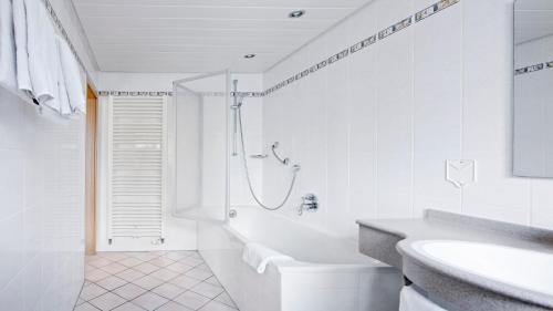 a white bathroom with a shower and a sink at Hotel Victoria in Weil am Rhein