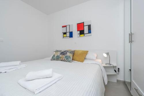 ein Schlafzimmer mit einem weißen Bett und einem Gemälde an der Wand in der Unterkunft Sunset mood modern ap with a pool for 6 in Novalja