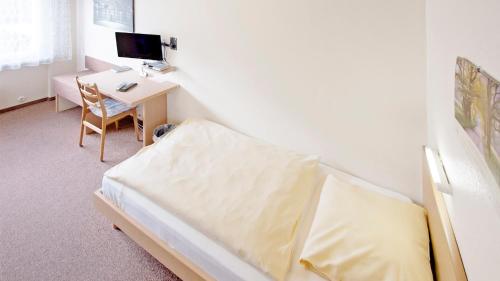 a bedroom with a bed and a desk with a computer at Hotel Victoria in Weil am Rhein