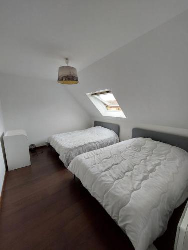 two beds in a white room with a window at Maison de ville in Dourdan