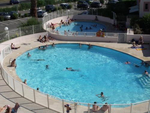 un groupe de personnes nageant dans une grande piscine dans l'établissement Appartement T2, 7 JOURS MINIMUM, Climatisé, 3 étoiles, 40m2 ,parking privé, Mer 300m, Wifi, Piscines, très propre, Ascenseurs, en étage, au Grau-du-Roi