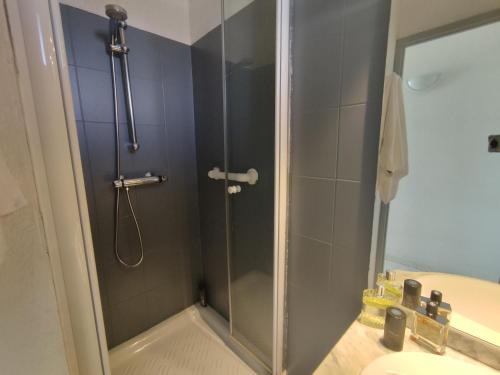 une douche avec une porte vitrée à côté d'un lavabo dans l'établissement Appartement 204, Natura Beach au village naturiste, au Cap d'Agde