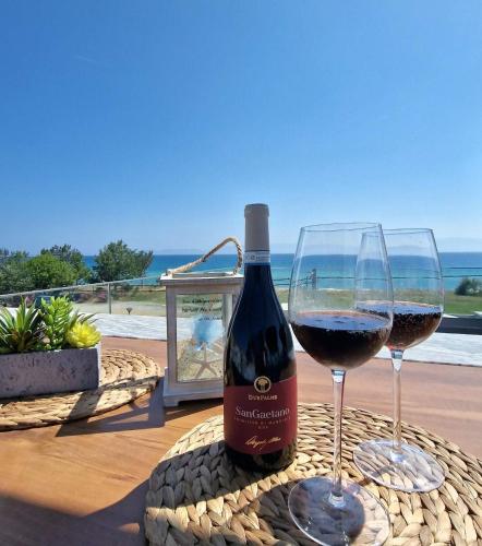 a bottle of wine sitting next to two glasses of wine at Морска къща ЕММА in Ofrínion