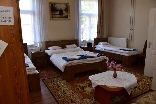 a room with two beds and two tables in it at Borostyán Vendégház in Nagykőrös