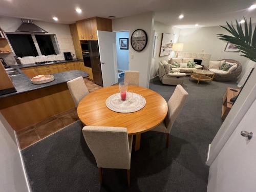a kitchen and living room with a wooden table and chairs at Waiake Beach Apartments in Auckland