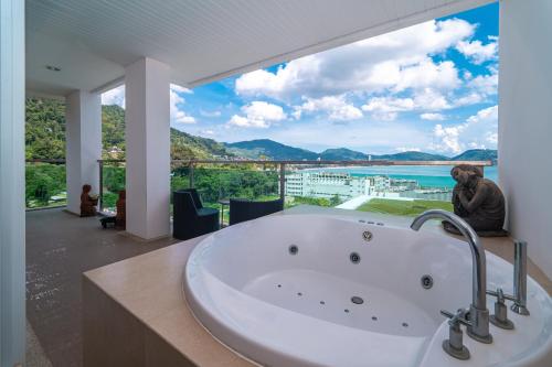 a large white tub in a bathroom with a large window at Patong Kalim Unparalleled Sea View B&B Resort in Patong Beach