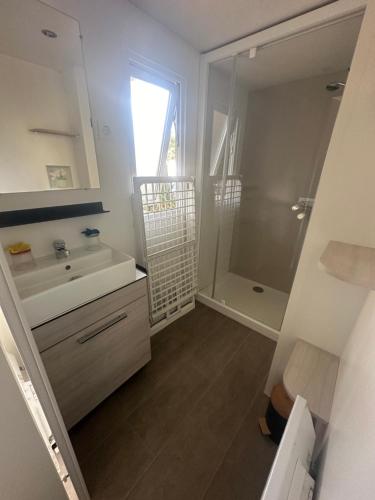 Un baño blanco con lavabo y ducha. en camping 4 Etoiles A ST JEANS-DE-MONTS Mobil home 4à6 pers, en Saint-Jean-de-Monts