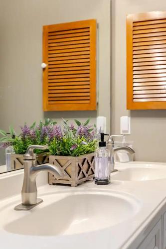 a bathroom sink with flowers in a basket on it at The Halcyon Days North Charleston in Charleston