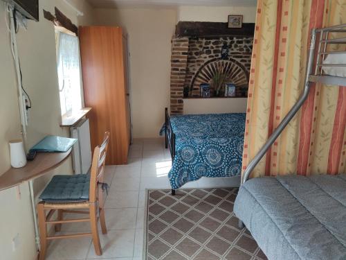 une chambre avec un lit, un bureau et une chaise dans l'établissement PETIT MAS COSY DU BORD DE LOIRE a 15 MM DU PARC LE PAL, à Diou