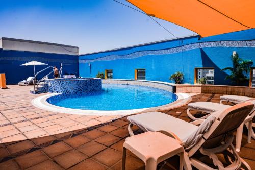 a large swimming pool with chairs and an umbrella at Grand Bellevue Hotel Apartment Dubai in Dubai