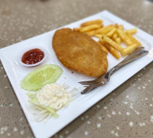 a plate with a fish and french fries and ketchup at AllOfUs GuestRoom in Kuala Lumpur