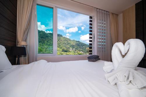 a bedroom with a white bed with a large window at Patong Kalim Unparalleled Sea View B&B Resort in Patong Beach