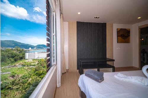 a bedroom with a bed and a window with a view at Patong Kalim Unparalleled Sea View B&B Resort in Patong Beach