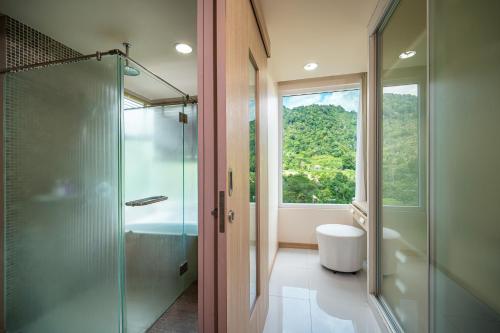 a bathroom with a shower and a toilet and a window at Patong Kalim Unparalleled Sea View B&B Resort in Patong Beach