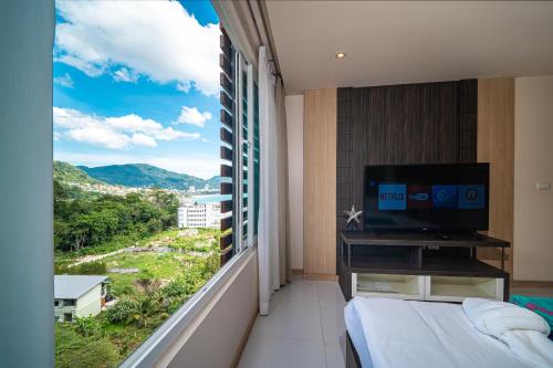 a bedroom with a large window with a bed and a television at Patong Kalim Unparalleled Sea View B&B Resort in Patong Beach