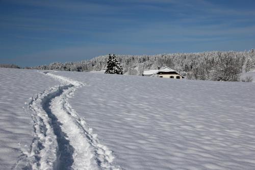 a trail in the snow with a house in the background at Studio 4 personnes, pied des pistes ski et VTT in Métabief