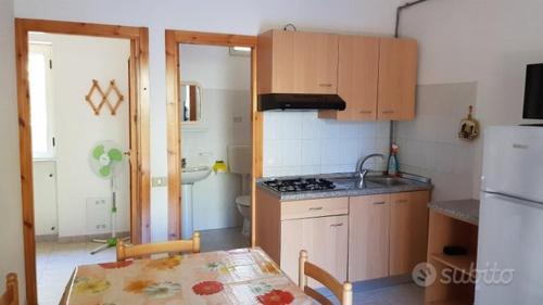 eine Küche mit einem Tisch, einer Spüle und einem Kühlschrank in der Unterkunft Residence Polidoro in Vieste