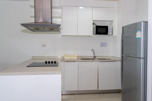 a kitchen with white cabinets and a stainless steel refrigerator at Patong Kalim Unparalleled Sea View B&B Resort in Patong Beach