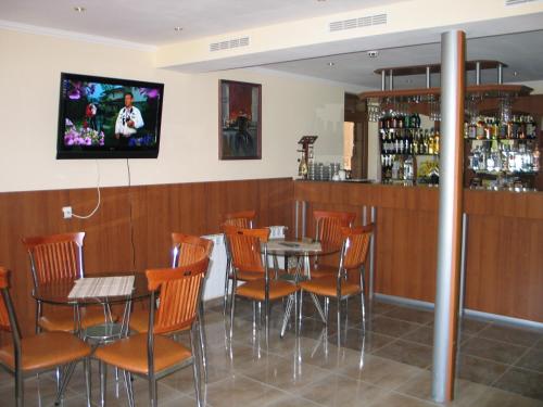 a bar with tables and chairs and a tv on the wall at Kovanlika Hotel in Razgrad