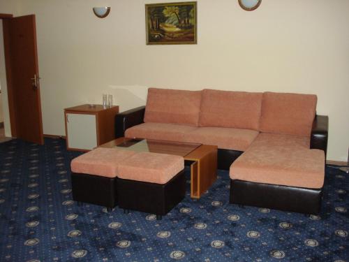 a living room with a couch and a ottoman at Kovanlika Hotel in Razgrad