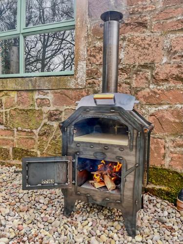 a wood fired oven sitting in front of a brick building at Stable Cottage, Gartocharn, Loch Lomond in Alexandria