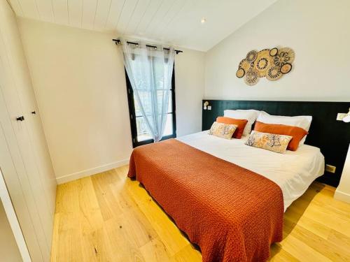 ein Schlafzimmer mit einem großen Bett mit einer orangefarbenen Decke in der Unterkunft La Villa des Matelots in La Flotte