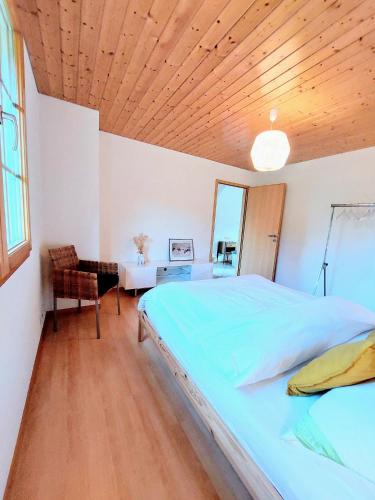 a bedroom with a large bed with a wooden ceiling at Sublime et calme 3,5p Terrasse et Jardin in Aubonne