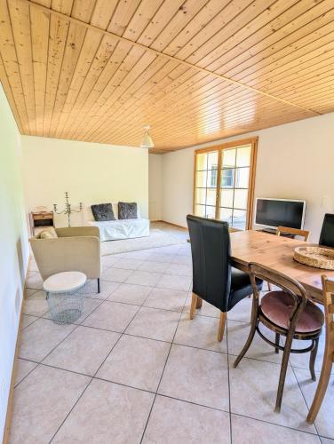 a living room with a wooden ceiling and a table at Sublime et calme 3,5p Terrasse et Jardin in Aubonne