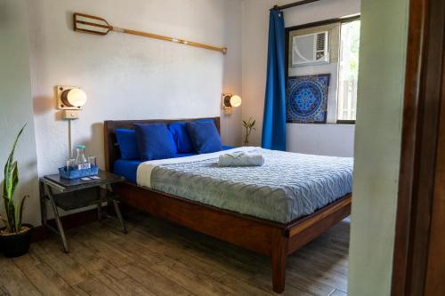 a bedroom with a bed with blue pillows at Island Lyfe Adventures in El Nido