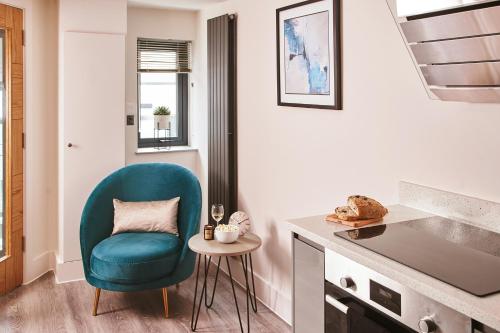 a living room with a blue chair and a table at The Moorings - Duplex apartment on Torquay Marina with Hot Tub in Torquay