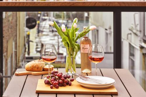 a table with two glasses of wine and a vase of flowers at The Moorings - Duplex apartment on Torquay Marina with Hot Tub in Torquay