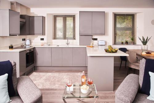 a kitchen and living room with white cabinets and a table at Harbour Breeze - On Torquay's iconic marina with hot tub in Torquay