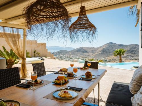 a table with plates of food and glasses of orange juice at Youtopia Ios Villas in Ios Chora