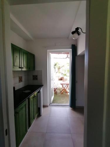 a kitchen with green cabinets and a door to a patio at La rosa dei venti in Procida