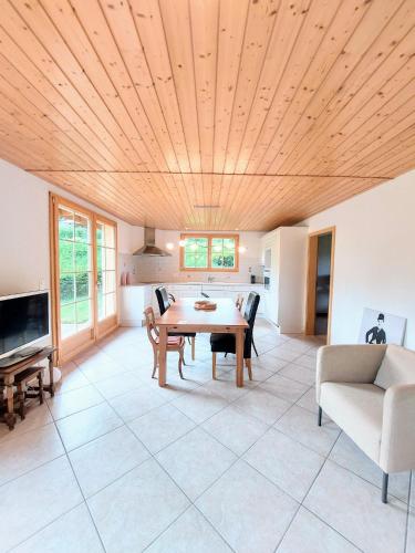 a living room with a wooden ceiling and a table at Sublime et calme 3,5p Terrasse et Jardin in Aubonne