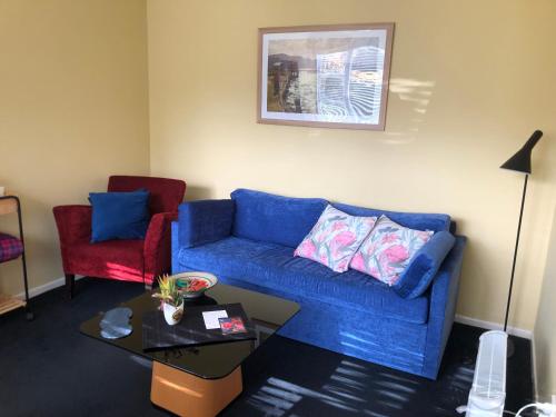 Close To Nature & City في ويلينغتون: غرفة معيشة مع أريكة زرقاء وكرسي احمر