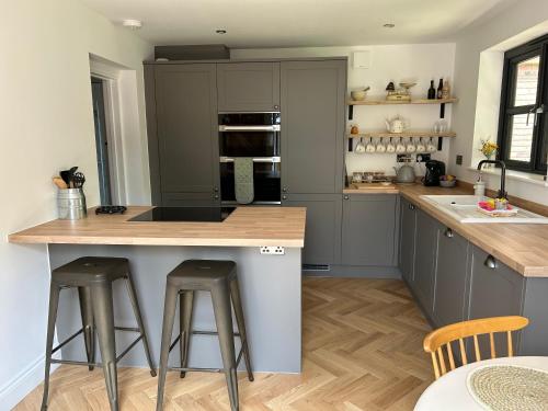 a kitchen with gray cabinets and a island with bar stools at Bee Cottage - Romsey in Romsey