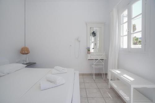 a white kitchen with a bench and a window at Nostos Sifnos in Apollonia