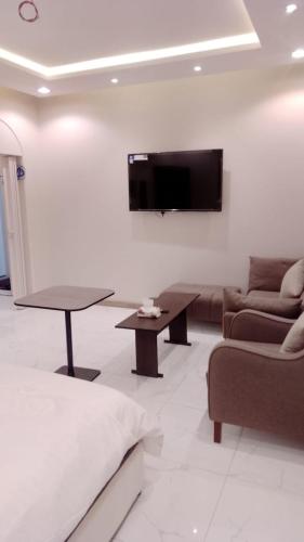 a living room with a couch and a tv on a wall at جوهرة البيعة للوحدات السكنية in Taif
