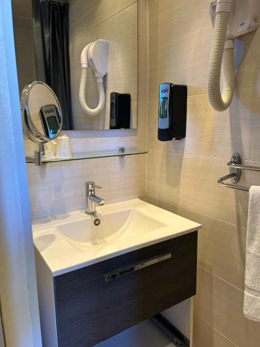 une salle de bain avec un lavabo et un miroir dans l'établissement Hôtel Le Bon Accueil, à Porto Ota