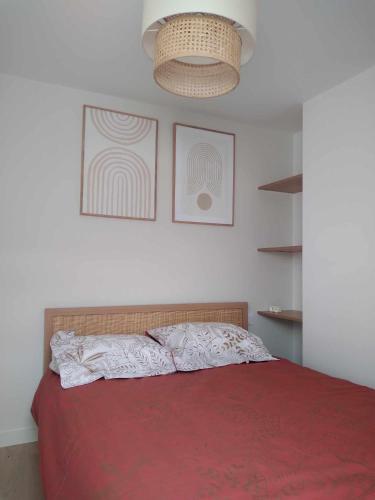 - une chambre avec un lit rouge et deux photos sur le mur dans l'établissement Duplex lumineux - 40m2 - 2 chambres - Balcon terrasse - Parking - Entierement renové en Mai 2024, à Cauterets