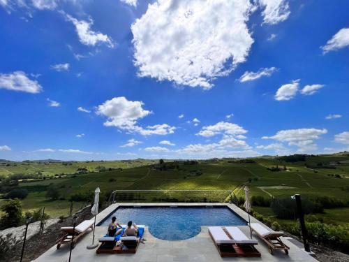 two people sitting in chairs next to a swimming pool at Tenuta Le More in Calosso
