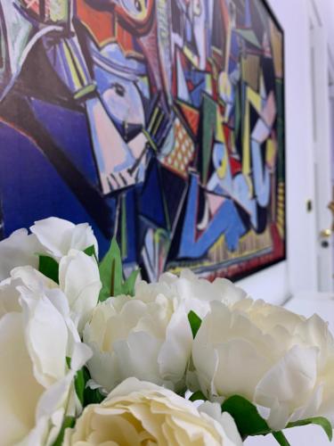 a bouquet of white flowers in front of a painting at suite cubè al centro storico vicino la scuola Vespucci con parcheggio su richiesta in Frattamaggiore