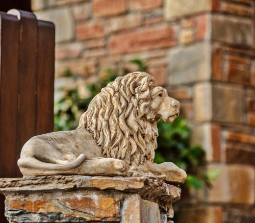 una estatua de un león sentada en una pared de piedra en Lions Nine, en Mouresi