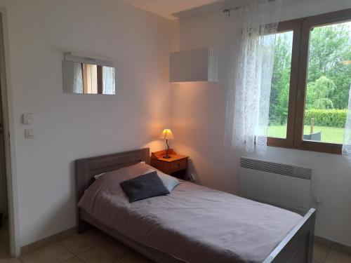 une chambre avec un lit avec une lampe et une fenêtre dans l'établissement Appartement avec jardin au pied de l'alpe d'huez, à La Garde