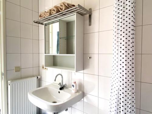a white bathroom with a sink and a mirror at Huisje De Deining in Ermelo